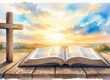 An open Bible and wooden cross glow in warm sunrise light.